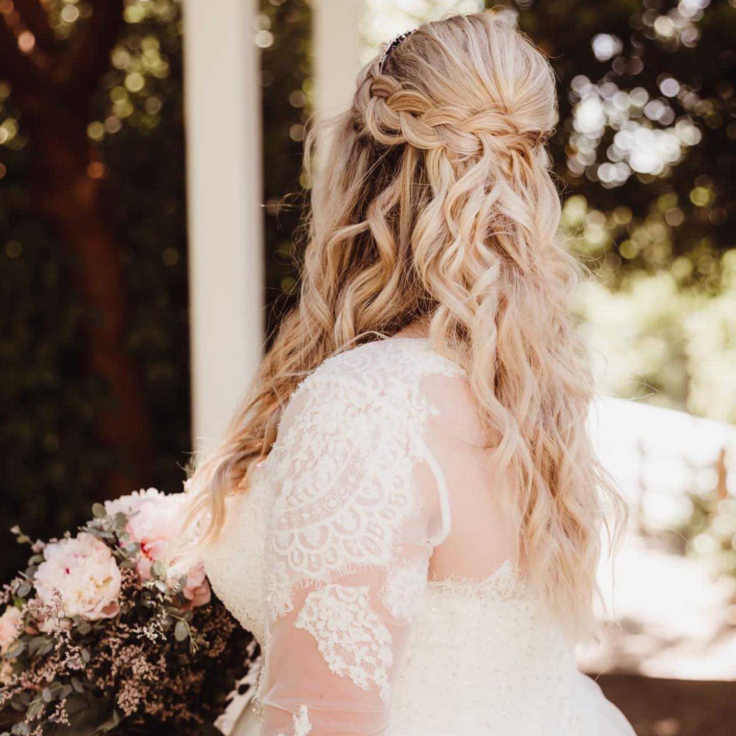braided half updo with loose flowing curls and flowers