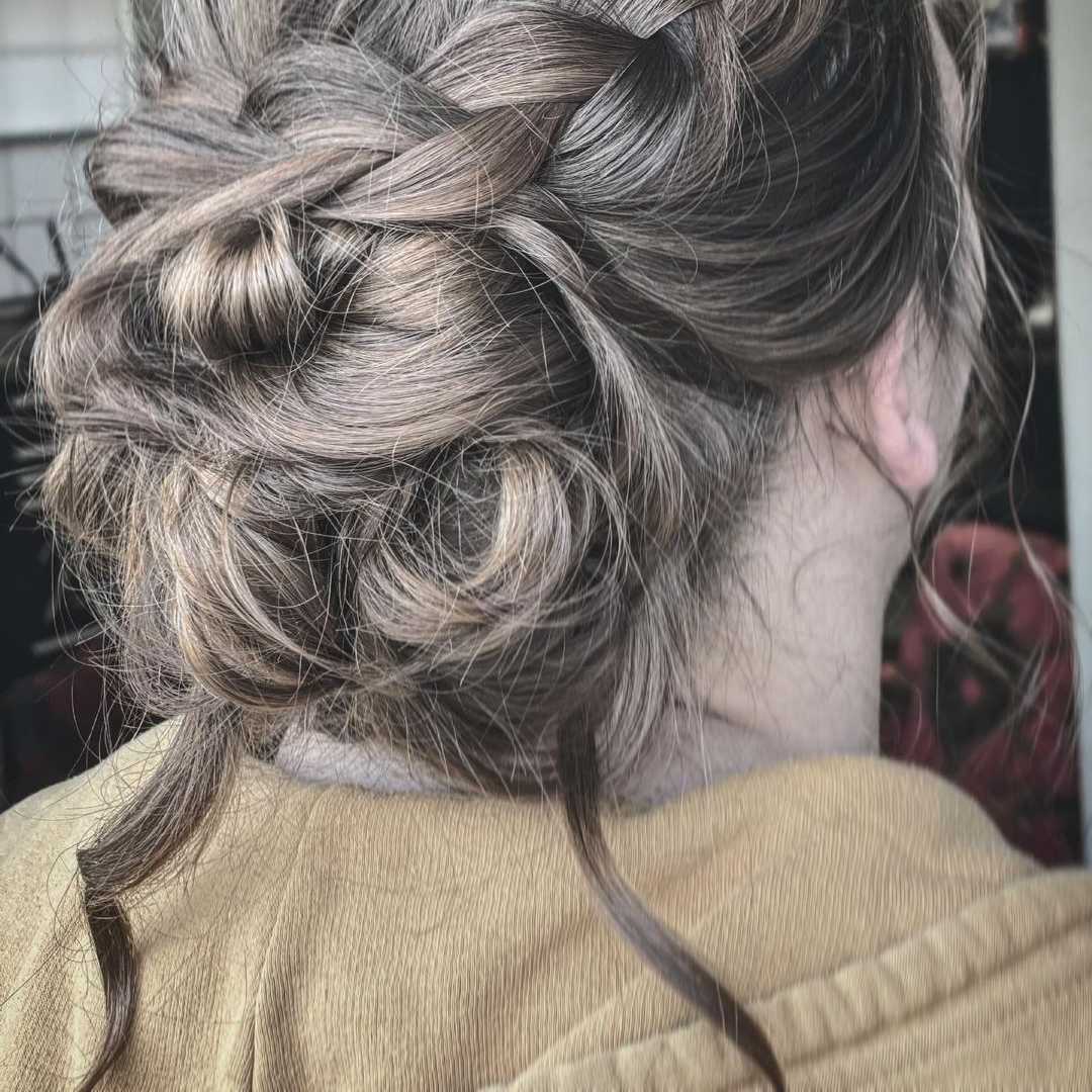 a braided updo into a thick bun with loose strands